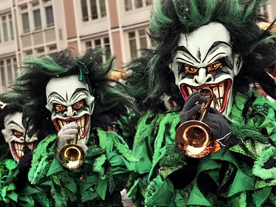Zwei Joker-Masken mit grünen Haaren und grünem Fransenkostüm beim Trompetespielen